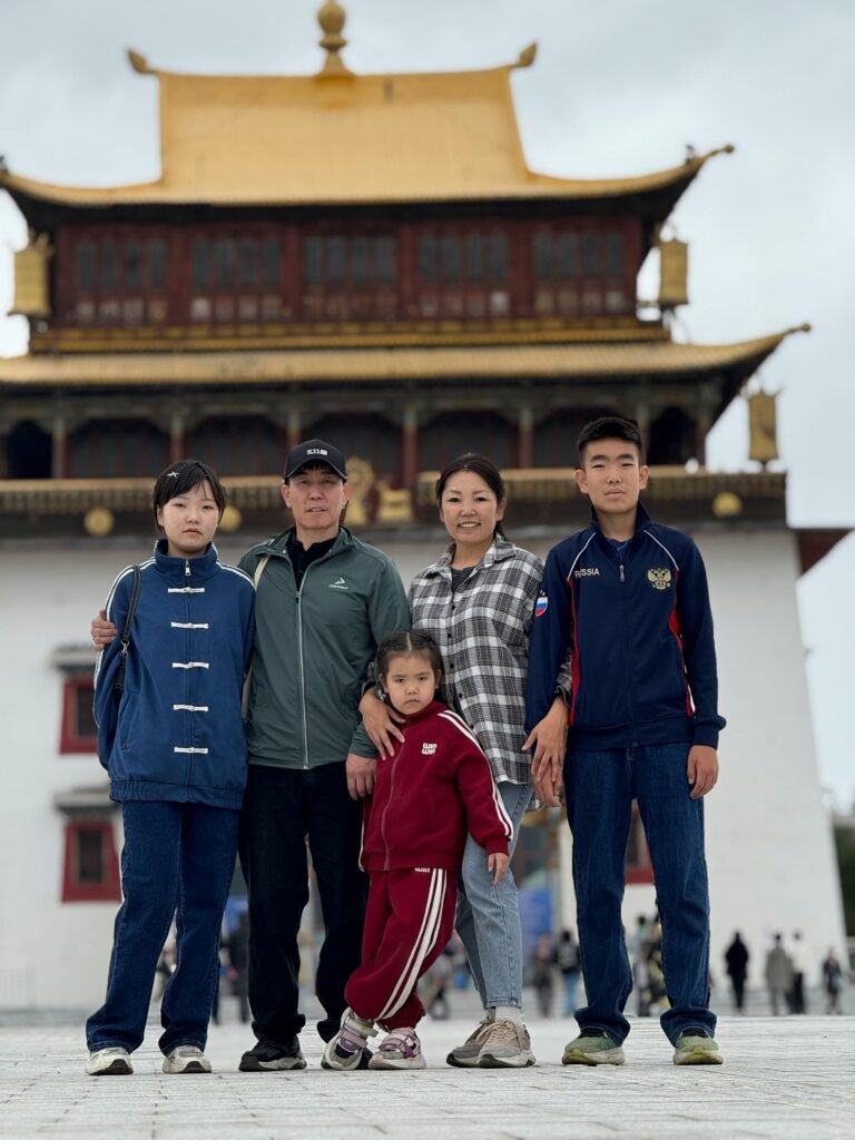 A family portrait in front of a traditional Buddhist temple with golden roof.